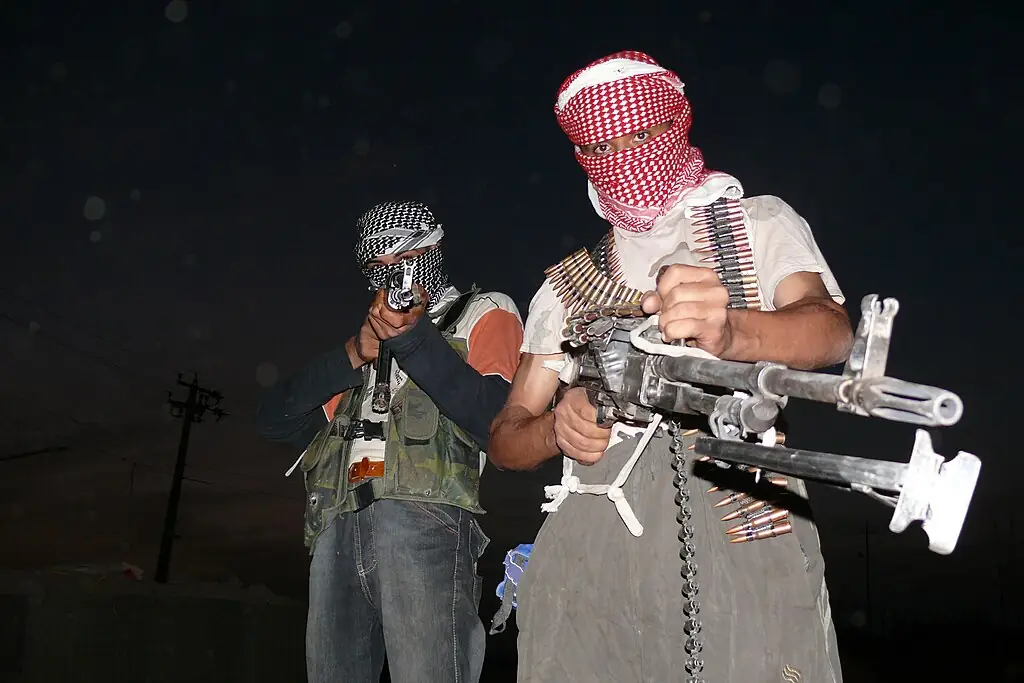 Two young insurgents wearing headscarfs and wielding weaponry and ammo.