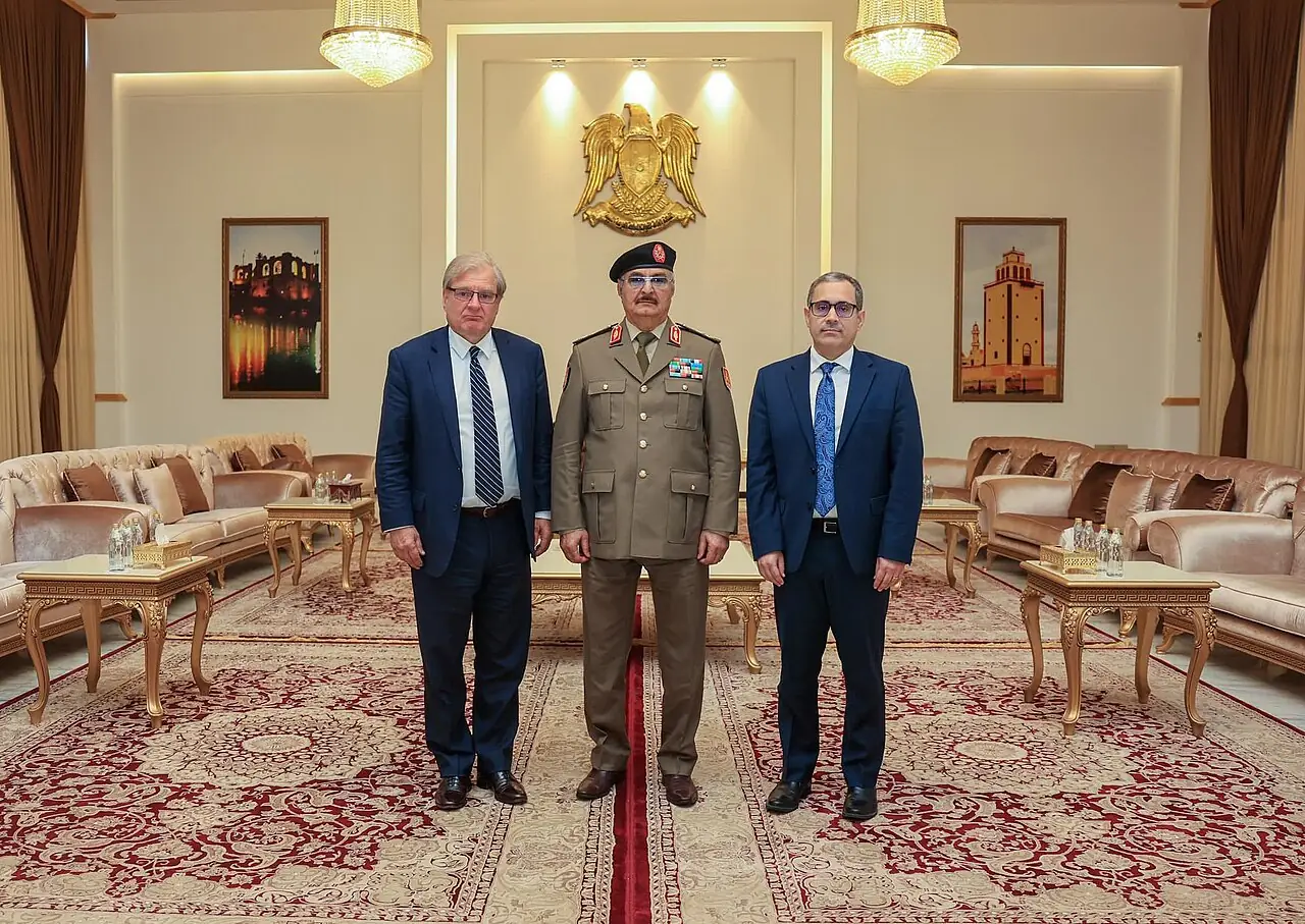 Richard Norland, Khalifa Haftar and Jeremy Berndth standing alongside each other in a decorated expensive looking room.