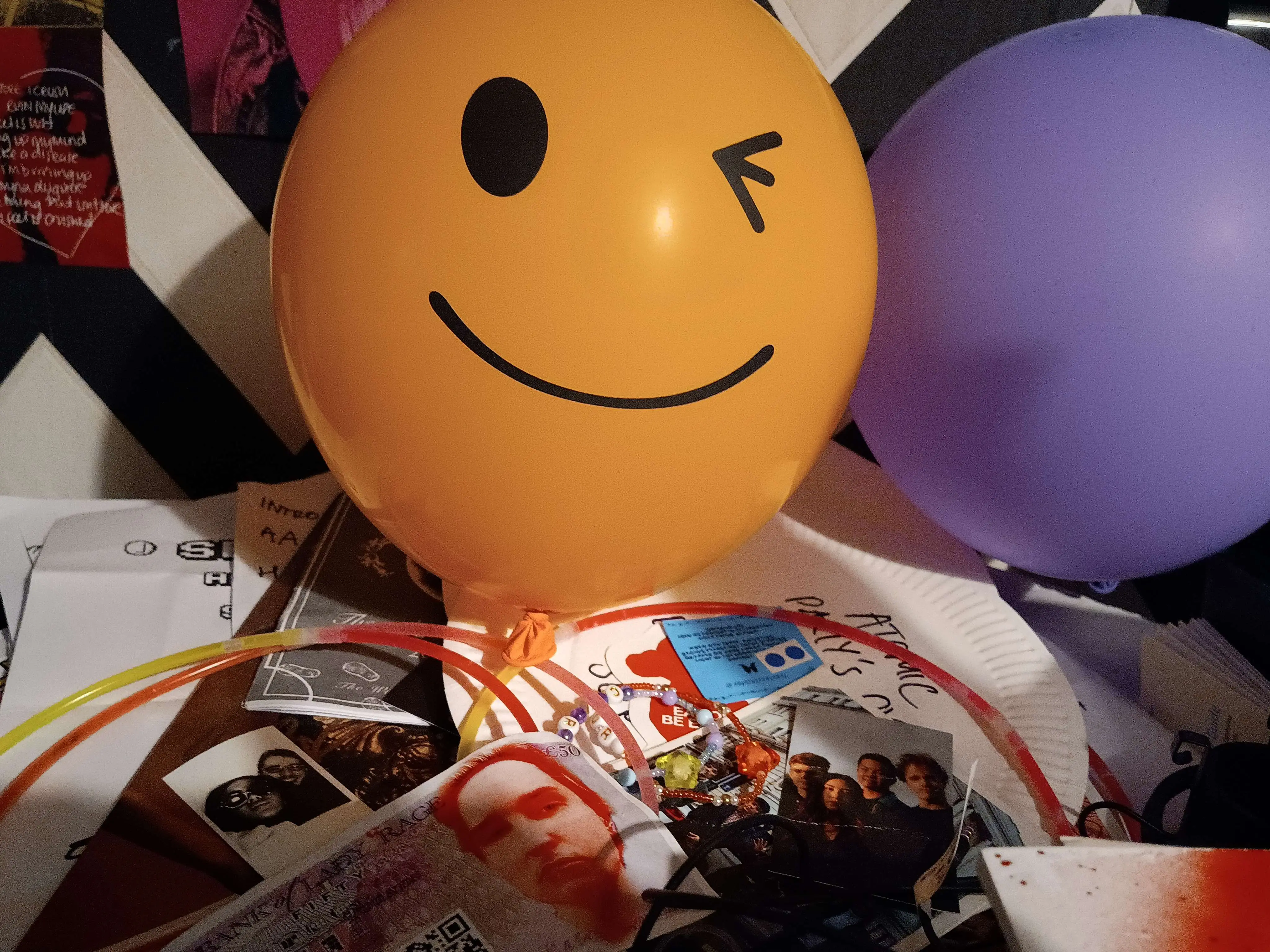 a big smiley balloon winking at the viewer among a bunch of mementos